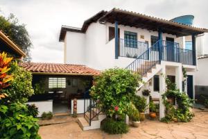 biały dom z niebieskimi balkonami i roślinami w obiekcie Pousada Casa da Cintia w mieście Diamantina