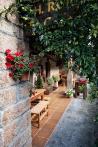 un patio con bancos de madera y flores rojas en Hotel Rural El Caserón, en Soto de Cangas