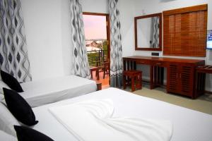 a hotel room with two beds and a desk and a window at Blue Sky Hotel Yala in Yala