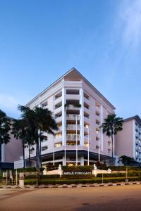 a large white building with palm trees in front of it at Melia Purosani Yogyakarta in Yogyakarta