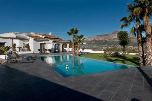 a swimming pool with palm trees and a house at Villa Orlando in Jávea