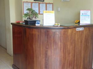 a wooden reception counter with a potted plant on top at Hotel Musafir Inn in Padang