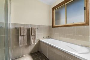 a bathroom with a bath tub and a mirror at Reflections Grabine Lakeside - Holiday Park in Bigga +39 photos