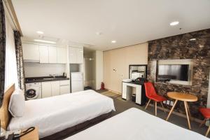 ein Hotelzimmer mit zwei Betten und einer Küche in der Unterkunft Dream Jeju Hotel in Seogwipo