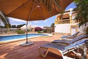 a group of lounge chairs with an umbrella next to a swimming pool at Sol in Jávea