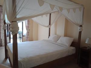 um quarto com uma cama de dossel com lençóis e almofadas brancos em Adila Warung and Homestay em Munduk