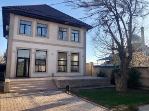 een wit huis met een boom ervoor bij Satti in Zharkent