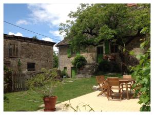 a patio with a table and chairs in front of a house at A L'Ombre du Tilleul in Comiac