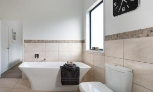 a bathroom with a white tub and a toilet at Blue Star Lodge in Kerikeri