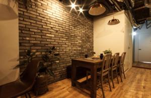 a dining room with a brick wall and a table and chairs at Guest House Re-worth Yabacho1 1F in Nagoya