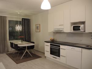 een keuken met witte kasten en een kleine tafel met stoelen bij Pearl in Raahe