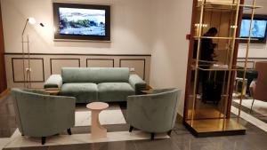 a living room with a couch and chairs and a tv at Hotel Roma in Trieste