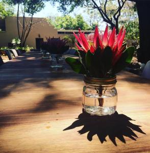 um frasco de flores vermelhas sentado numa mesa em Pierneef's Kraal em Pretoria