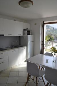 une cuisine avec des placards blancs et une table avec des chaises dans l'établissement appartamenti Casa Palazzina, à Malcesine