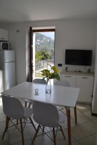 une cuisine avec une table et des chaises blanches ainsi qu'une fenêtre dans l'établissement appartamenti Casa Palazzina, à Malcesine