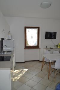 une cuisine blanche avec une table et une fenêtre dans l'établissement appartamenti Casa Palazzina, à Malcesine