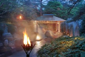仙台仙台秋保温泉 篝火の湯 緑水亭的花园内的火坑,花园内设有一个凉亭