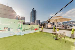 a rooftop patio with a table and an umbrella at Guesthouse Dear Moon in Busan