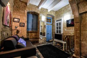 a living room with a couch and a tv at Historic Townhouse in Birgu Center in Vittoriosa
