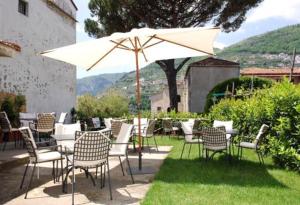 een groep stoelen en tafels met een paraplu bij Hotel Toro in Ravello