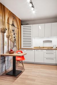 a kitchen with white cabinets and a wooden table at Krakow For You Budget Apartments in Krakow