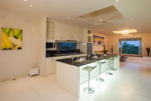 a kitchen with white cabinets and a island with bar stools at Noah Villa and Chapel in Jimbaran