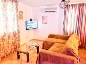 a living room with a couch and a tv at Romantic maisonette in the heart of Pythagoreio LH door in Pythagoreio