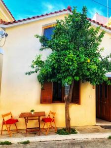 a table and chairs and a tree in front of a house at Romantic maisonette in the heart of Pythagoreio LH door in Pythagoreio