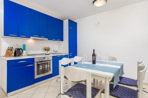 a kitchen with blue cabinets and a table with chairs at Apartments in pinewood near the sea in Mali Lošinj