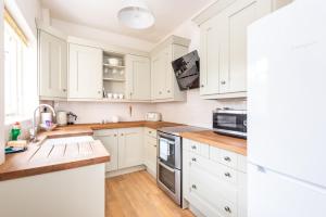 cocina blanca con armarios blancos y suelo de madera en Charming Base for 6 Near Bishy Rd - Pass the Keys en York