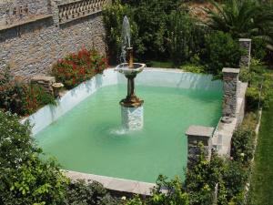 a fountain in a pool of green water at Parathyro Sto Aigaio 1 in Tinos