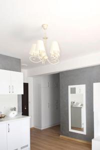 a kitchen with a chandelier and white cabinets and a mirror at Stela Apartments in Obzor