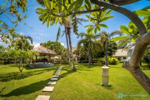 un jardin avec des palmiers et un sentier dans l'établissement Villa Segara Murti - Stylish Beachfront Villa!, à Banjar