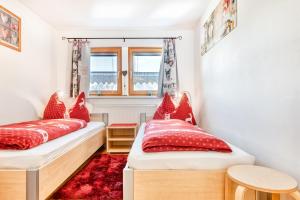 2 camas en una habitación pequeña con almohadas rojas en Chalet Fischer by A-Appartments en Bürserberg