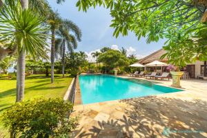 a swimming pool in a yard with palm trees at Villa Segara Murti - Stylish Beachfront Villa! in Banjar