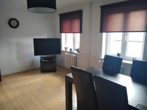 uma sala de estar com televisão e uma mesa com cadeiras em Apartament Centrum em Szczecinek
