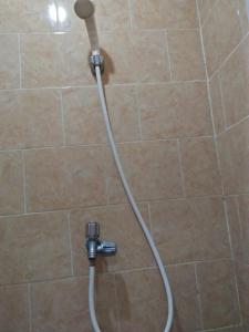 a shower with a hose in a tiled bathroom at Made Roejas Homestay in Uluwatu