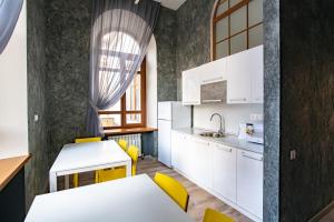 a kitchen with white cabinets and a table and yellow chairs at 1915 Hostel in Vladivostok