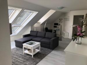 sala de estar con sofá negro y mesa en eifelTIME - Ferienwohnung en Bad Münstereifel