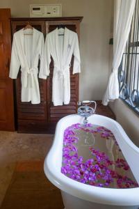 eine Badewanne mit lila Blumen im Bad in der Unterkunft Serenity on the Lake in Kalemera