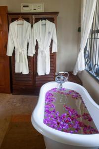 a bath tub filled with purple flowers in a bathroom at Serenity on the Lake in Kalemera