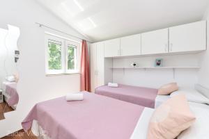 Cette chambre blanche dispose de deux lits et d'une fenêtre. dans l'établissement Peace and relaxation Villa Didov dvor, à Vinjerac