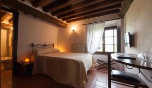 a bedroom with a bed and a desk and a window at Relais Fontevivo in Fontevivo