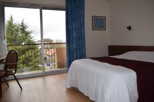 a bedroom with a bed, chair and a window at hotel le Soli in Saint-Julien-en-Genevois