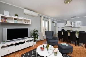 a living room with a television and a dining room at Villa Elder ZadarVillas in Donji Lepuri