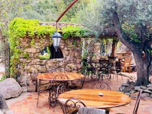 a patio with tables and chairs and a stone wall at Ranch Campo Palombaggia in Porto-Vecchio