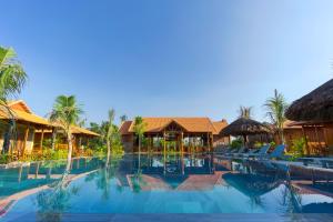 a resort swimming pool with chairs and palm trees at Island Lodge Phu Quoc in Phu Quoc