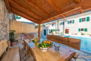 a patio with a wooden table and a swimming pool at Villa Petrovi Dvori ZadarVillas in Benkovac