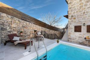 a patio with a swimming pool next to a stone building at Villa Laurana ZadarVillas in Pakoštane