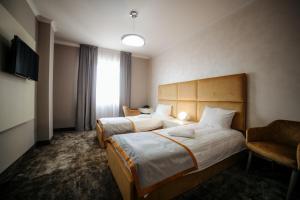 une chambre d'hôtel avec deux lits et une chaise dans l'établissement Royal Class Hotel, à Cluj-Napoca